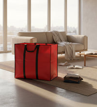Red storage bag with black handles next to folded clothes on a beige background